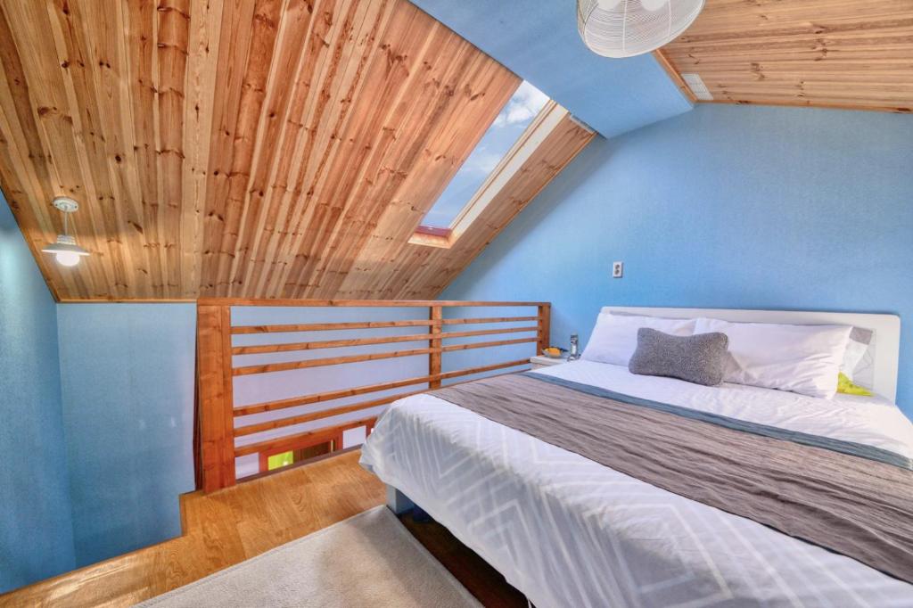 杨平郡Yoon and Park Pension的一间卧室设有一张蓝色墙壁和木制天花板的床。