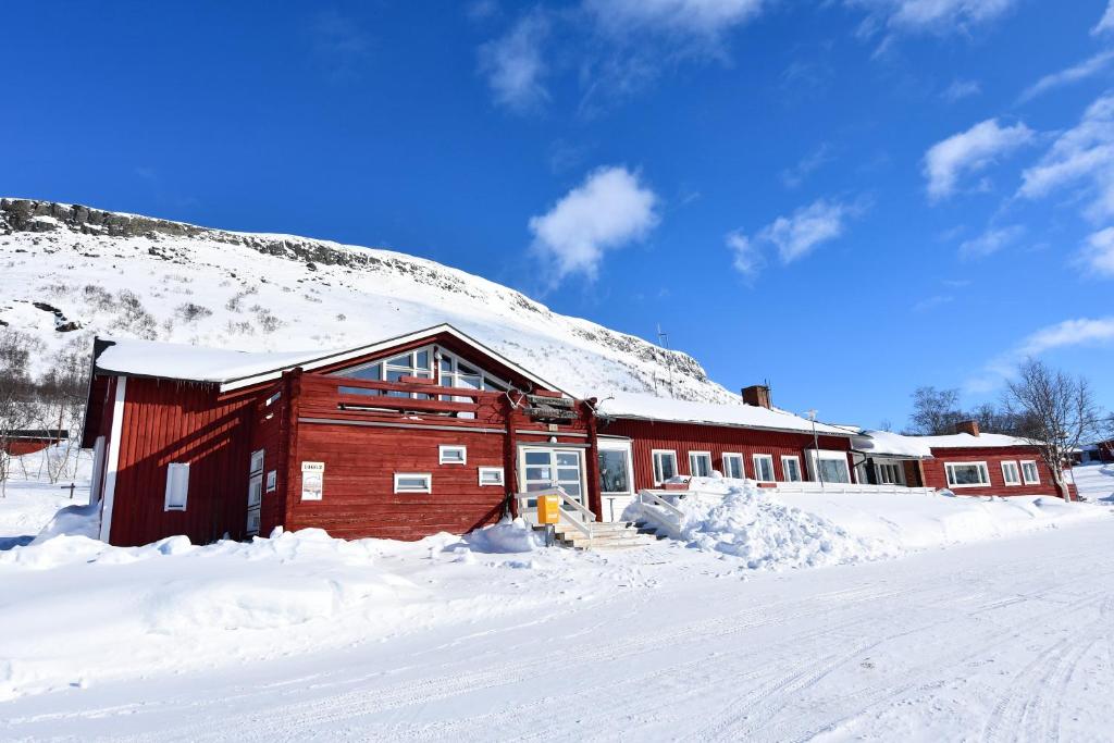 基尔匹斯扎我维Kilpisjärven Retkeilykeskus Rooms的雪中一座红色的建筑,有雪覆盖的山