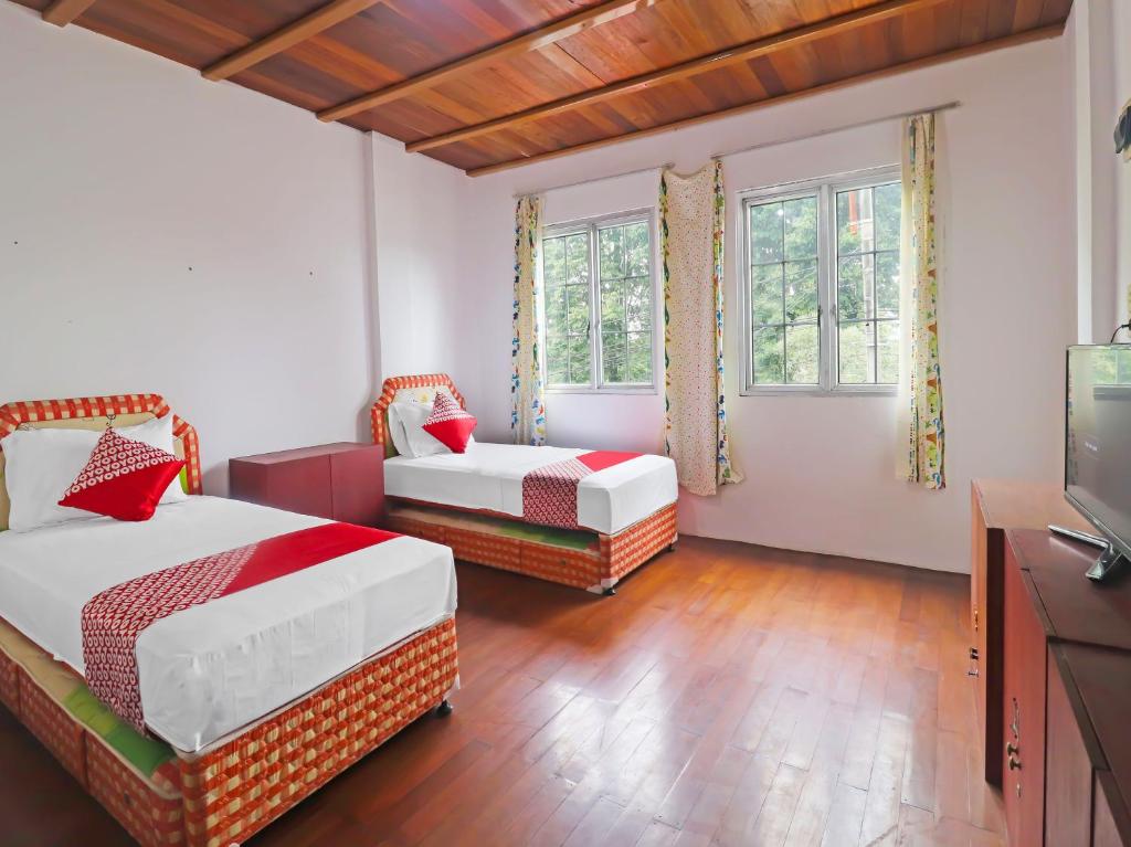 占碑市OYO 91807 Kemalasari Guesthouse的一间卧室配有两张床和一台平面电视