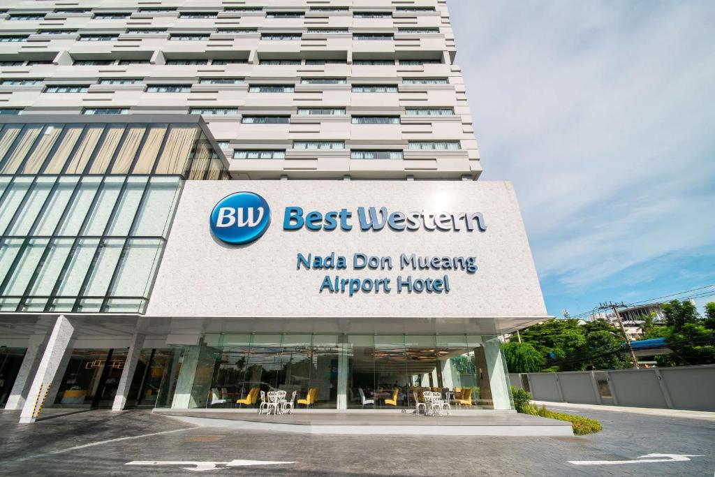 曼谷Best Western Nada Don Mueang Airport hotel的一座建筑,上面标有读取最佳西装机场酒店的标志