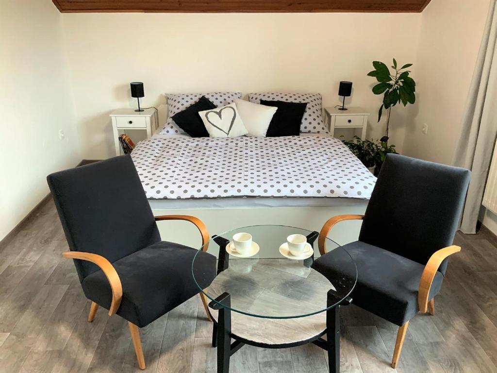 豪斯庭Apartmán v podkroví的一间卧室配有一张床、两把椅子和一张玻璃桌