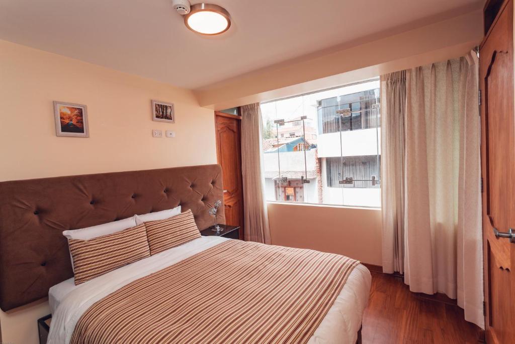 库斯科Hotel Las Quenas的一间卧室设有一张大床和一个窗户。
