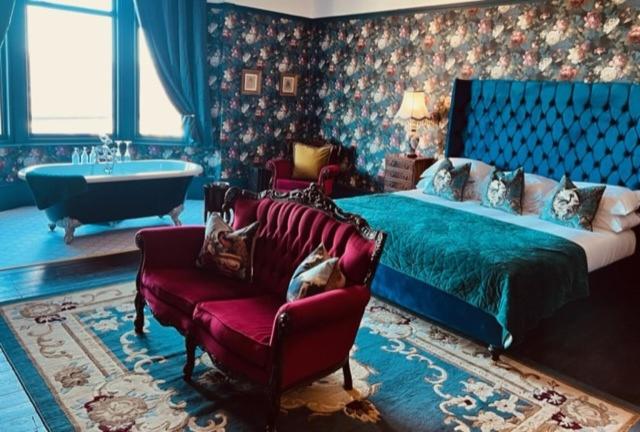 伊尔克利The Gin Lounge Rooms的一间卧室配有一张床、一把椅子和一个浴缸