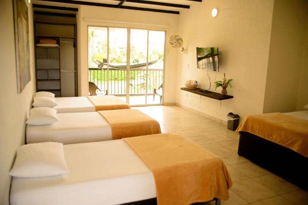 金巴亚Finca Hotel Loma Verde的酒店客房设有四张床和阳台。