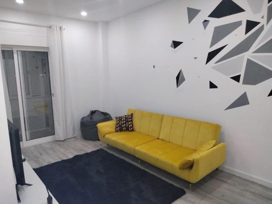 阿莫拉Lisbon, 3 bedroom apartment in Amora , 15 min from the beach的客厅里一张黄色的沙发,墙上有黑色的箭头