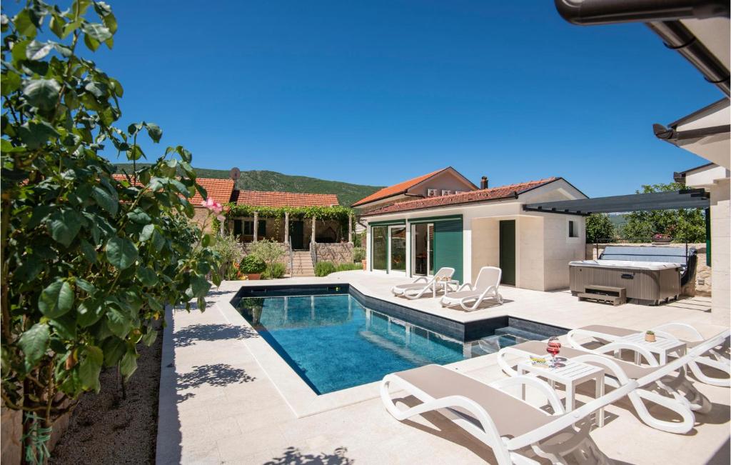 SlivnoGorgeous Home In Slivno With Heated Swimming Pool的一个带白色椅子的游泳池以及一座房子