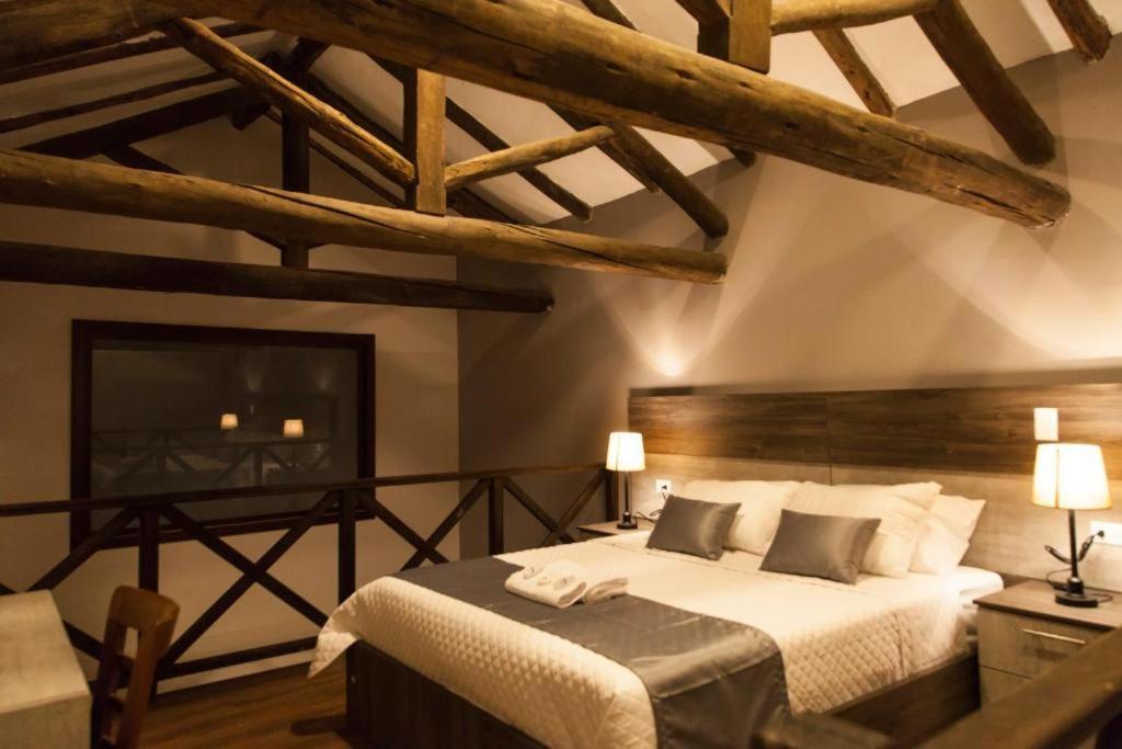 昆卡Hotel Raymipampa的一间带一张大床的卧室,位于一个拥有木制天花板的房间