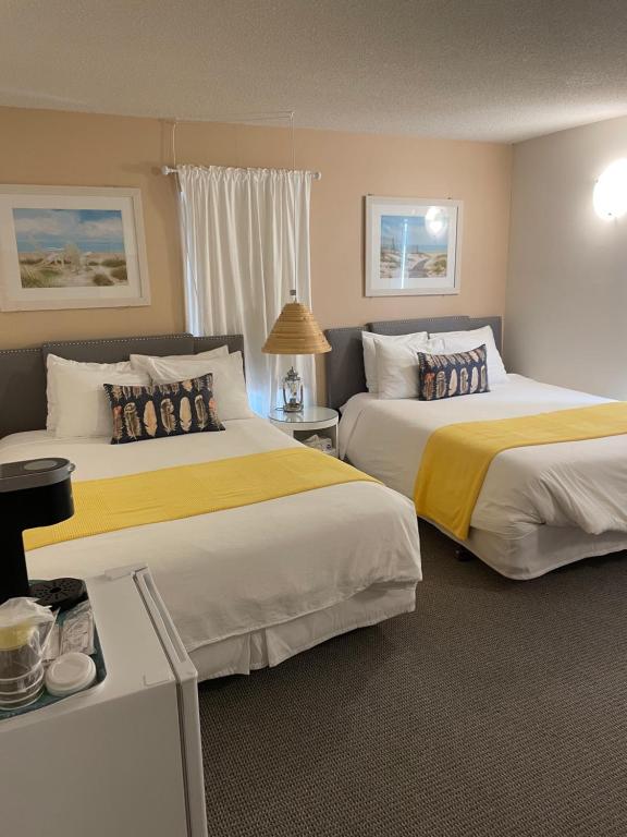 埃尔金港Paradise Inn On the Beach的酒店客房带两张带黄床单的床