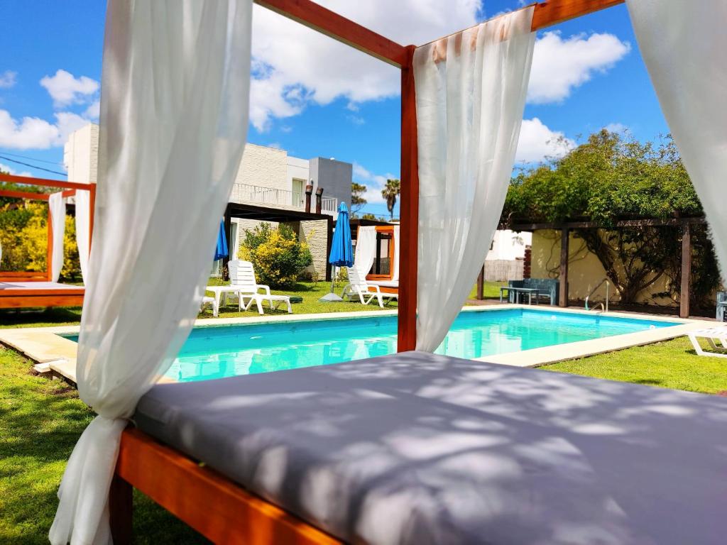 皮里亚波利斯Las Martinas Piriapolis的一间卧室设有一张华盖床,毗邻一个游泳池