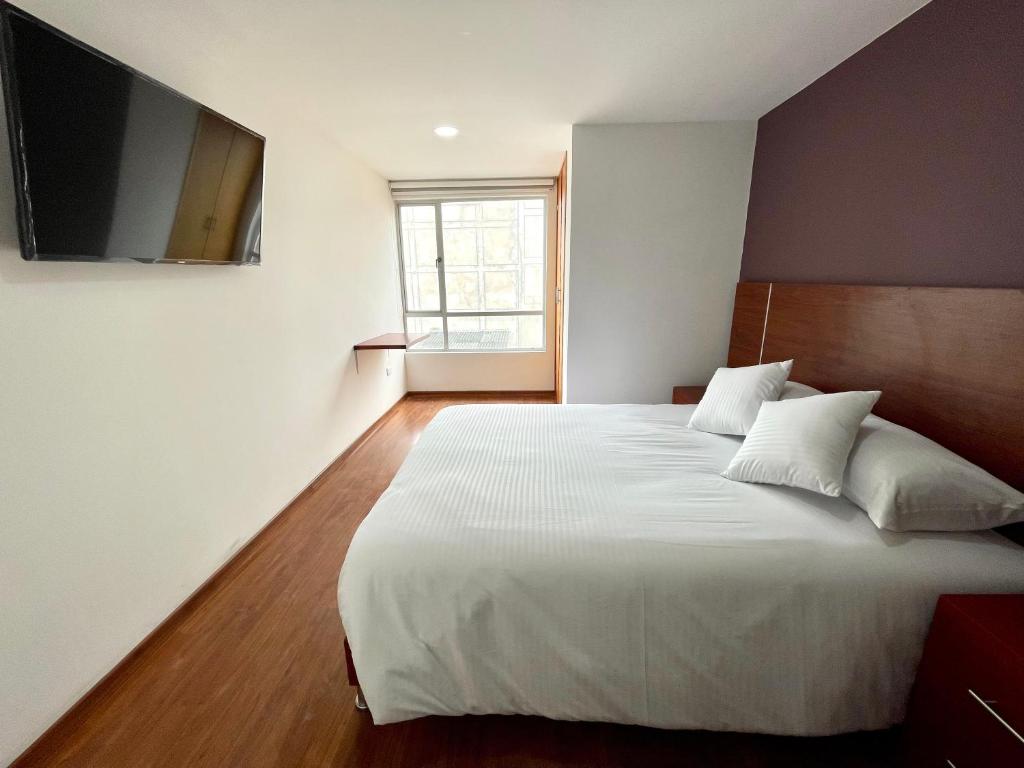 帕斯托HOTEL HOME的卧室配有一张白色床,墙上配有电视