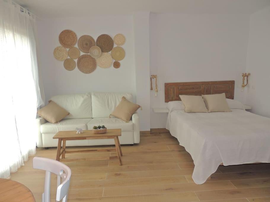 拉萨维纳Suite La Savina Formentera con vistas al mar的一间卧室配有一张床、一张沙发和一张桌子