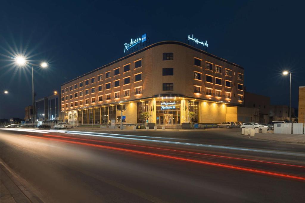 布赖代Radisson Blu Hotel, Buraidah的夜间的建筑,汽车在上面加速