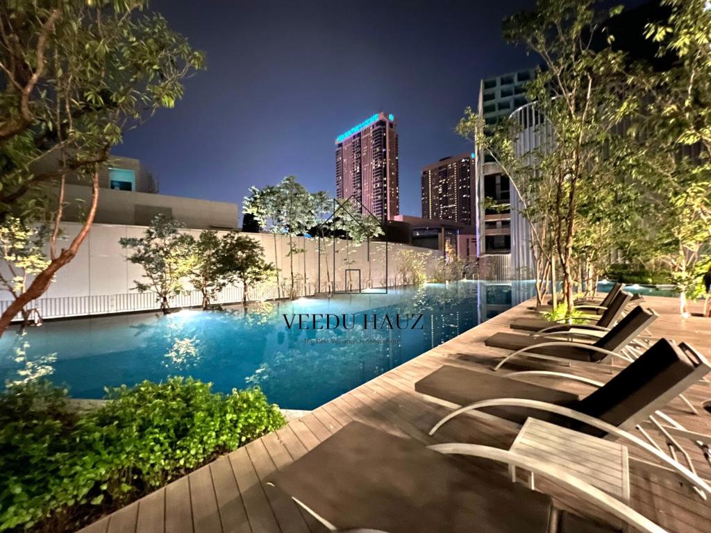 吉隆坡Lucentia Residences BBCC at Lalaport Kuala Lumpur by Veedu Hauz的城市的游泳池,晚上有躺椅