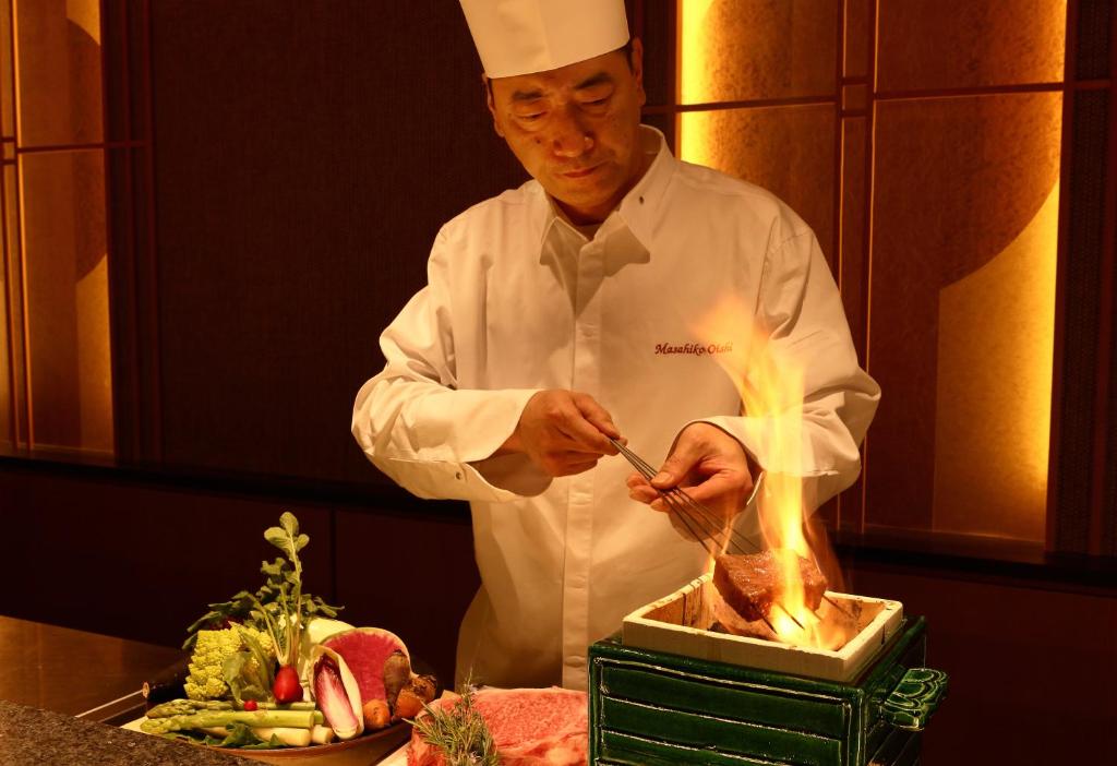 米子市Yado Shiontei的厨房里的厨师在烧烤架上烹饪食物