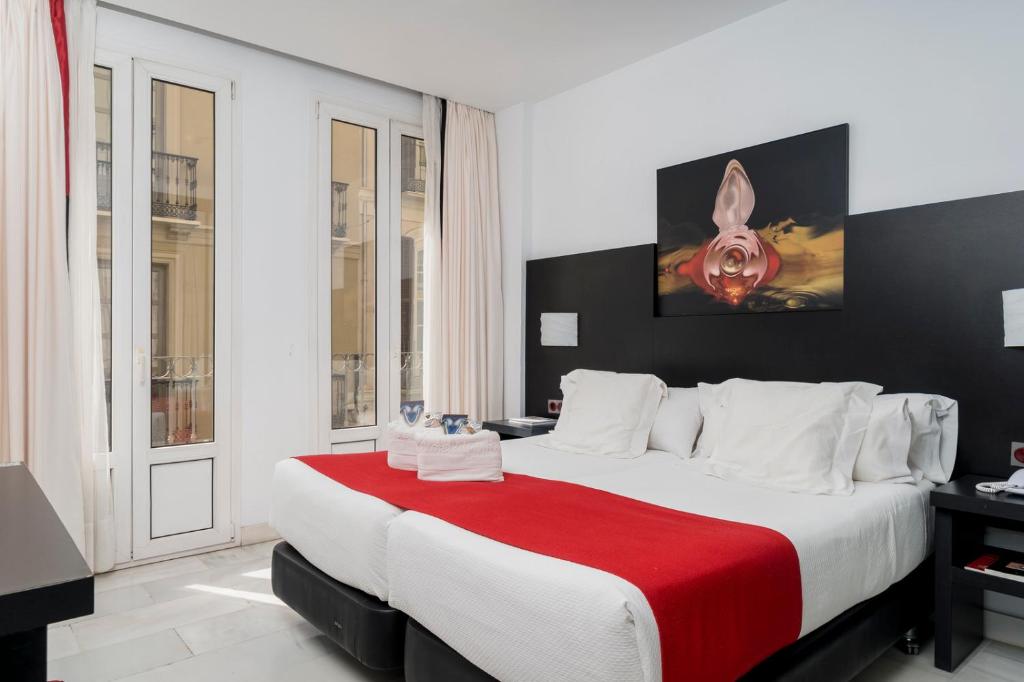 马拉加画家酒店的一间卧室配有一张带红色毯子的大床
