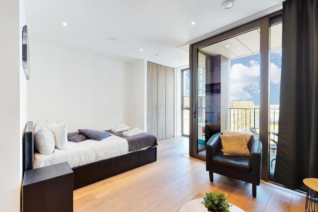 伦敦Superb Studio in Greenwich with balcony & roof top的一间带一张床和一把椅子的卧室以及一个阳台