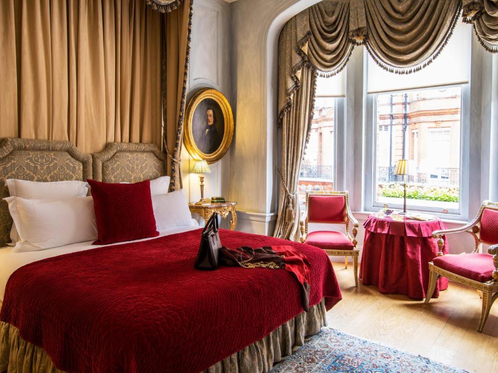 伦敦圣多米尼哥别墅酒店的一间卧室配有一张带红色毯子的床和两把椅子