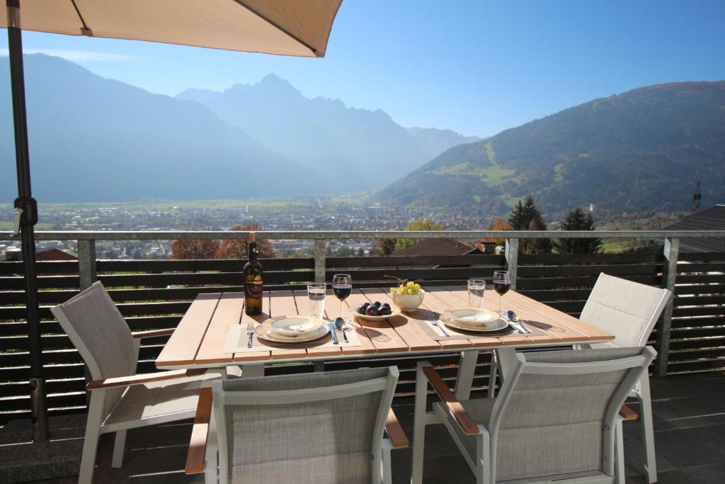 利恩茨Sun Apartments - with Dolomiten Panorama的阳台上配有一张带椅子和遮阳伞的木桌