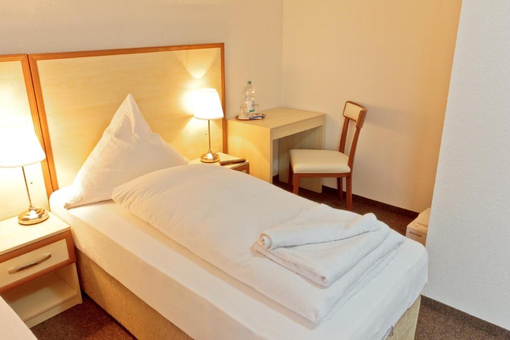 莱茵河畔威尔Hotel Ganita Weil am Rhein的配有一张床和一把椅子的酒店客房