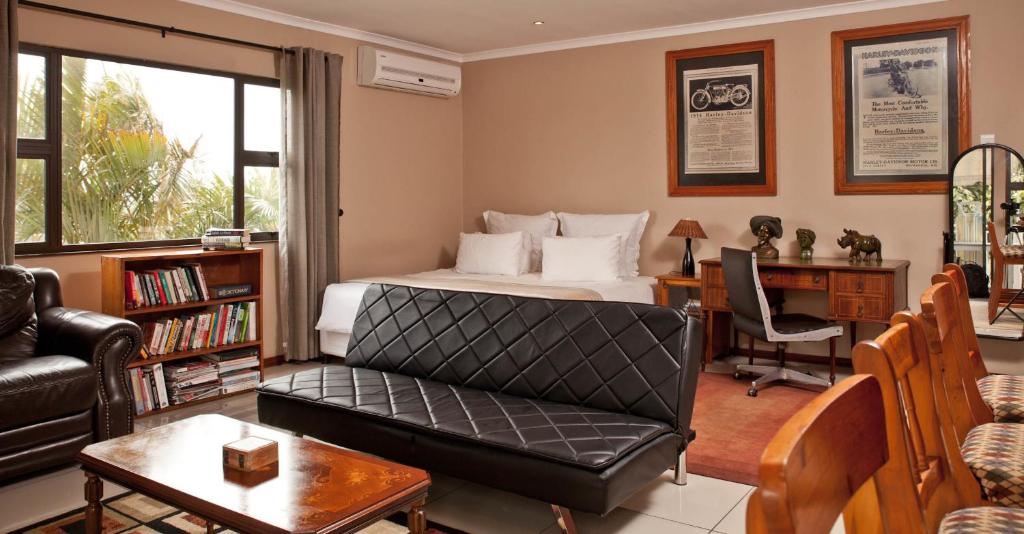 德班卡林顿旅馆的一间卧室配有一张床、一张桌子和一张沙发