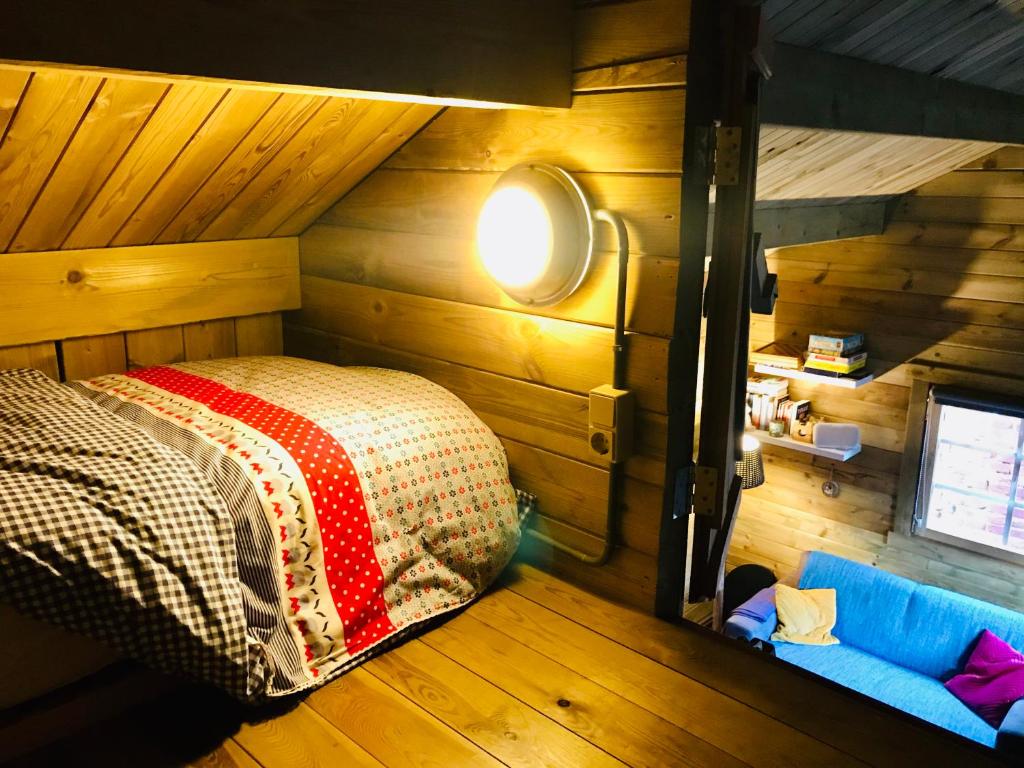 巴特纽维斯Tiny House Andersom Anders的卧室配有一张床铺,位于带木墙的房间内