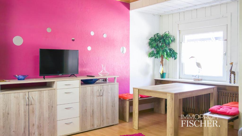 莫尔斯Zimmer im Herzen von Moers的客厅设有粉红色的墙壁,配有电视