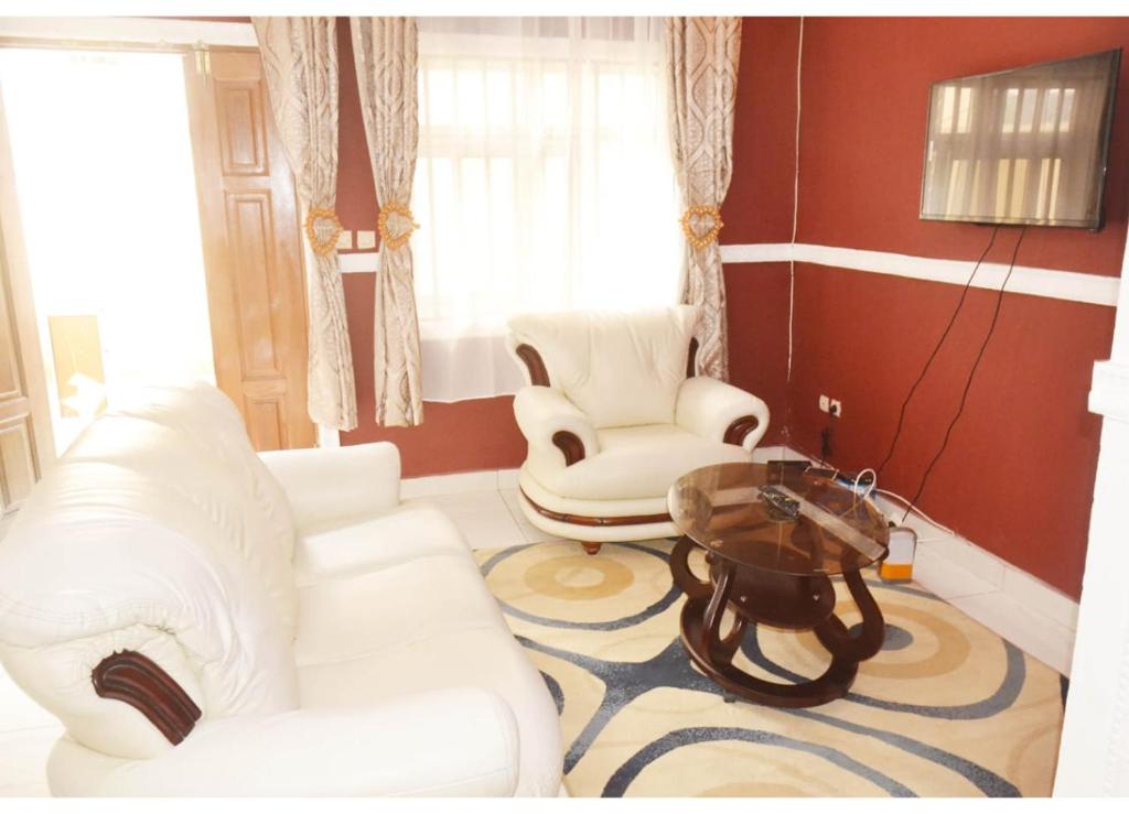 雅温得Appartement New Stading YAOUNDE - MIMBOMAN MAETURE的客厅配有白色沙发和两把椅子