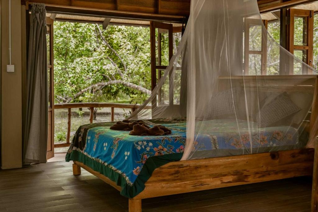 考索Monkey Mansion - Jungalows & Tours的窗户客房内的一张带天蓬的床