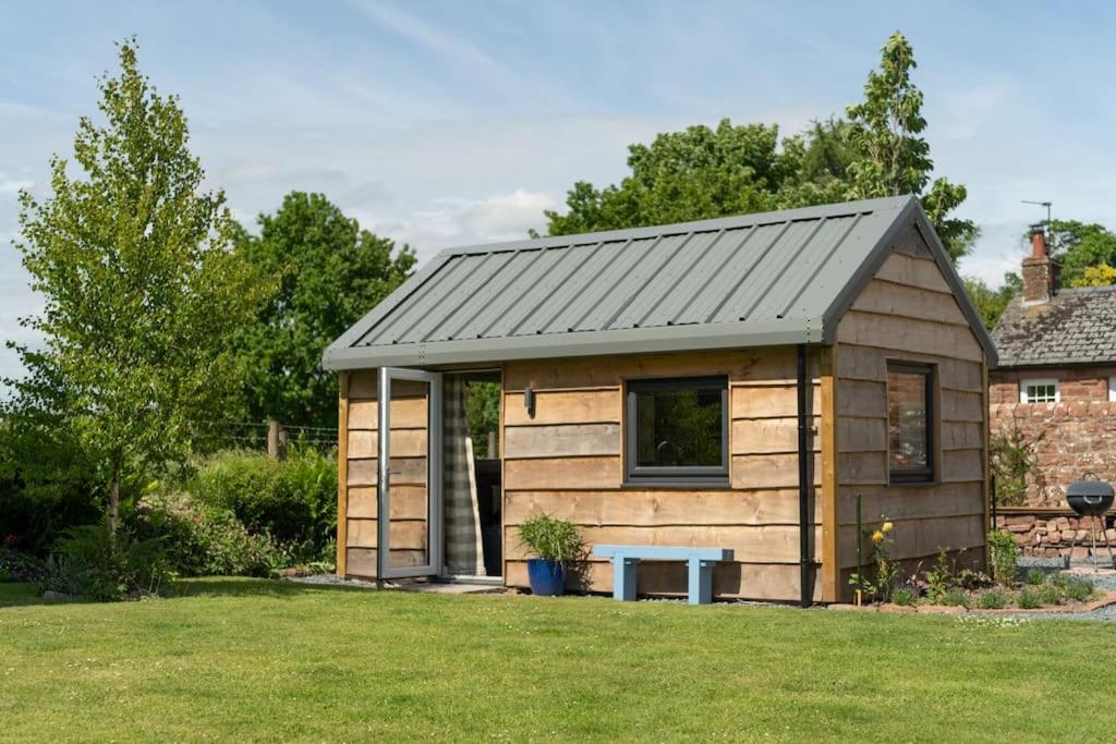 布兰普顿La'al Cabin, tiny home, unique space Eden Valley Cumbria的庭院中带长凳的小木房子