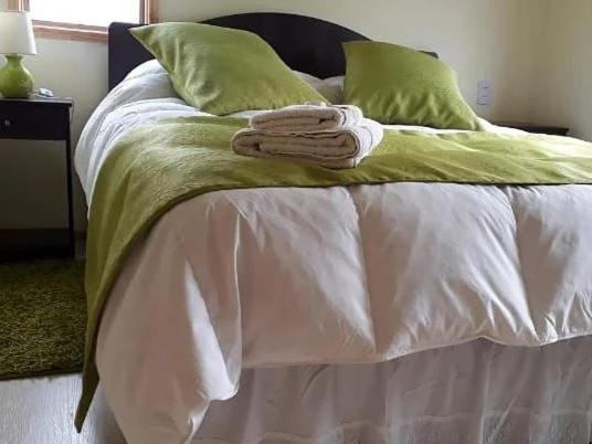 纳塔列斯港Cabañas Frange的一张带绿色枕头的白色床和毛巾