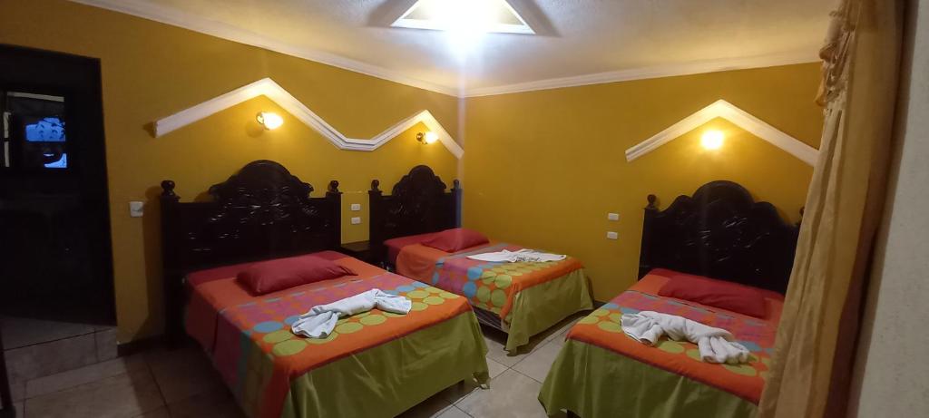圣佩德罗拉拉古纳Hotel Tinamit的黄色墙壁的房间里设有三张床