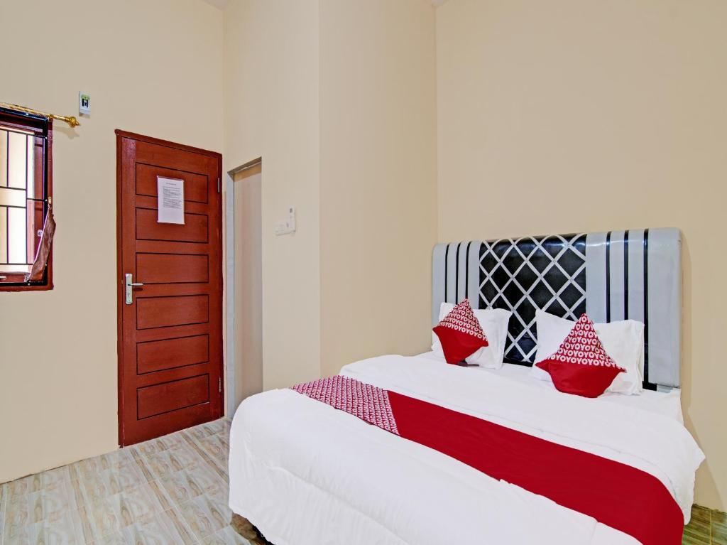 北干巴鲁OYO 91835 Djasur Kost的一间卧室配有红色和白色枕头的床