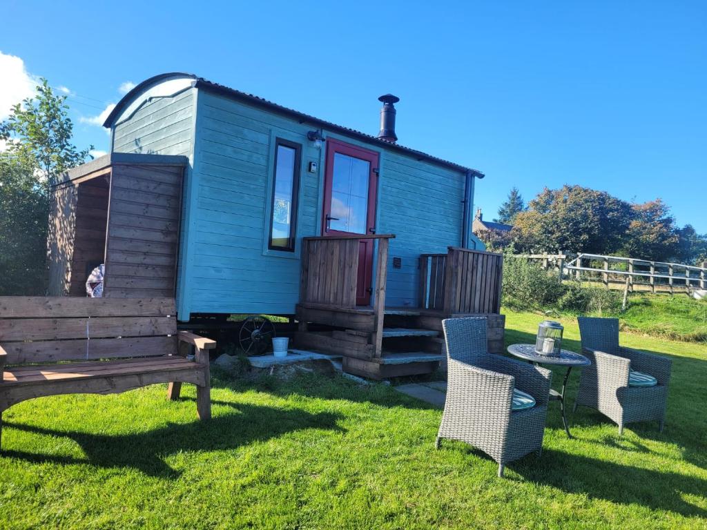 绿岛The Shepherds Hut at Forestview Farm的蓝色的小房子,配有长凳和椅子