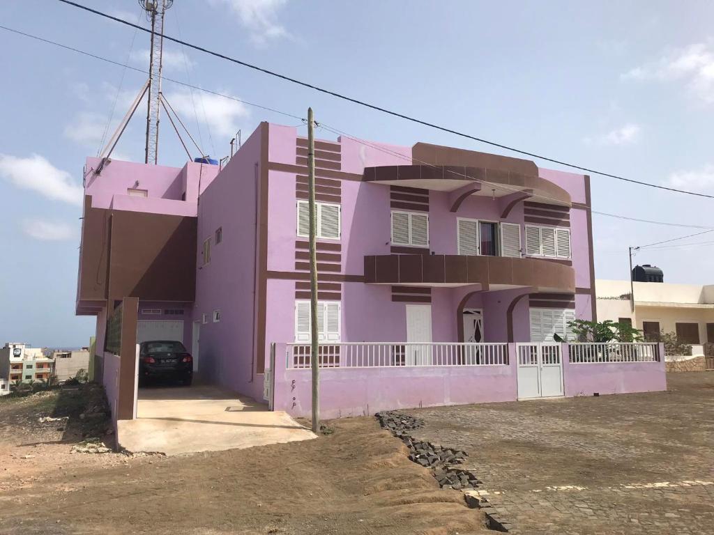 埃斯帕戈斯CA FILO的一座粉红色的房子,前面有一辆汽车
