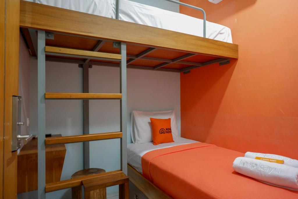 梭罗KoolKost @ Inep Kayu Jebres的两张双层床,带橙色墙壁