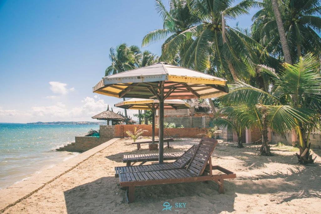 Ấp Khánh Phước (1)Sky Home的一个带两个长椅和遮阳伞的海滩