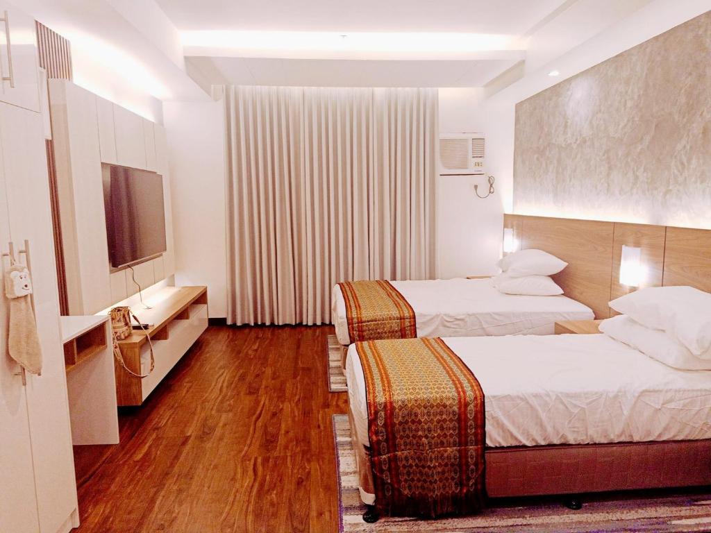 达沃市Cozy Suite Studio type condo in Matina Enclaves的酒店客房设有两张床和电视。