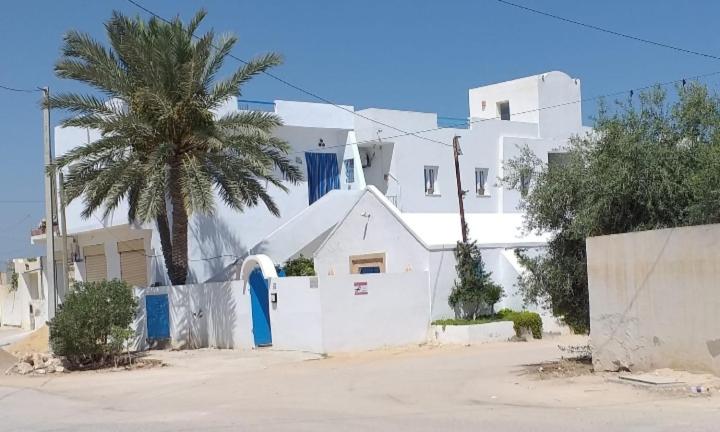 乌姆苏克Dar Janis Djerba دار يانيس جربة的一座白色的建筑,前面有棕榈树