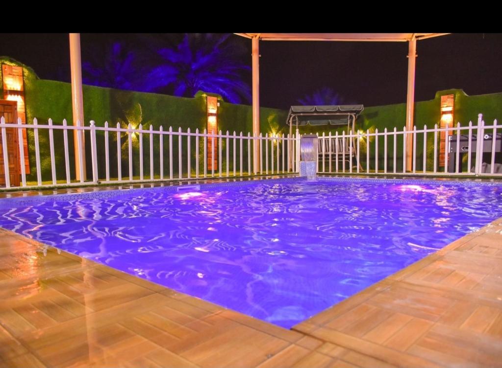 Ḩifrīشالية البندرvip的紫色的游泳池,晚上有白色的围栏