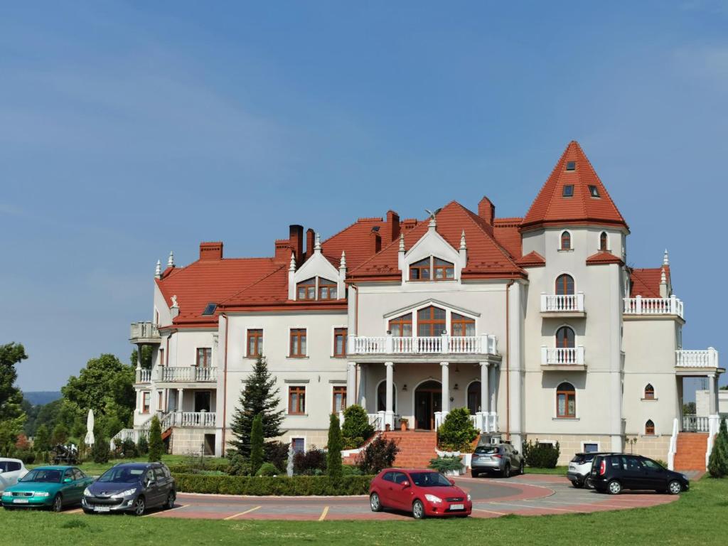 WodzisławPałac Koronny Noclegi & Wypoczynek的一座大型白色房子,停车场有车辆停放