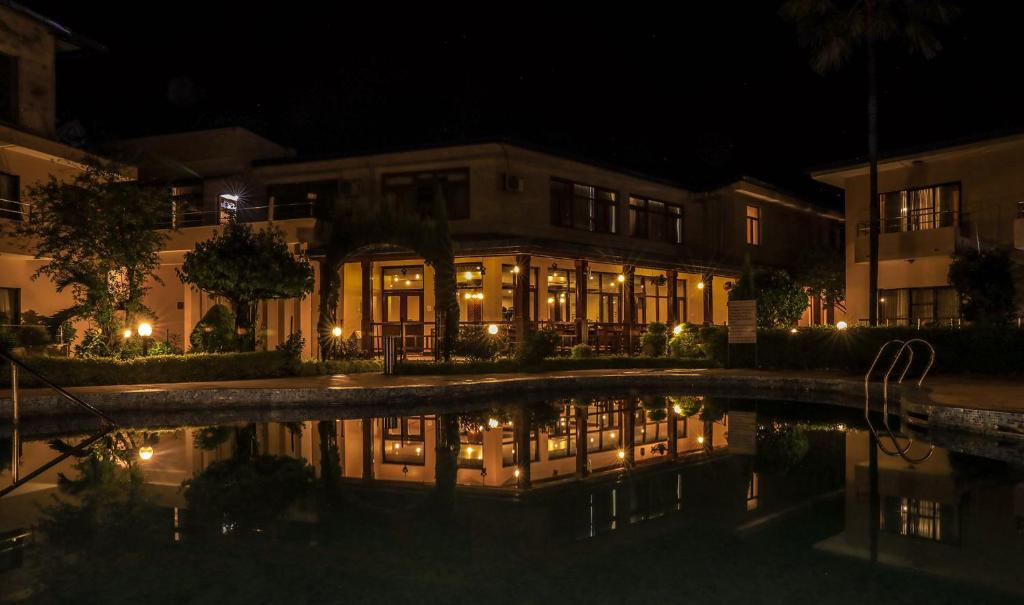 巴拉特布尔Bharatpur Garden Resort的一座在水中反射的夜间建筑