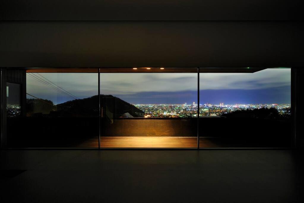 札幌Sapporo boukyo Luxury house 5 pax Free Parking的窗户,晚上可欣赏到城市美景
