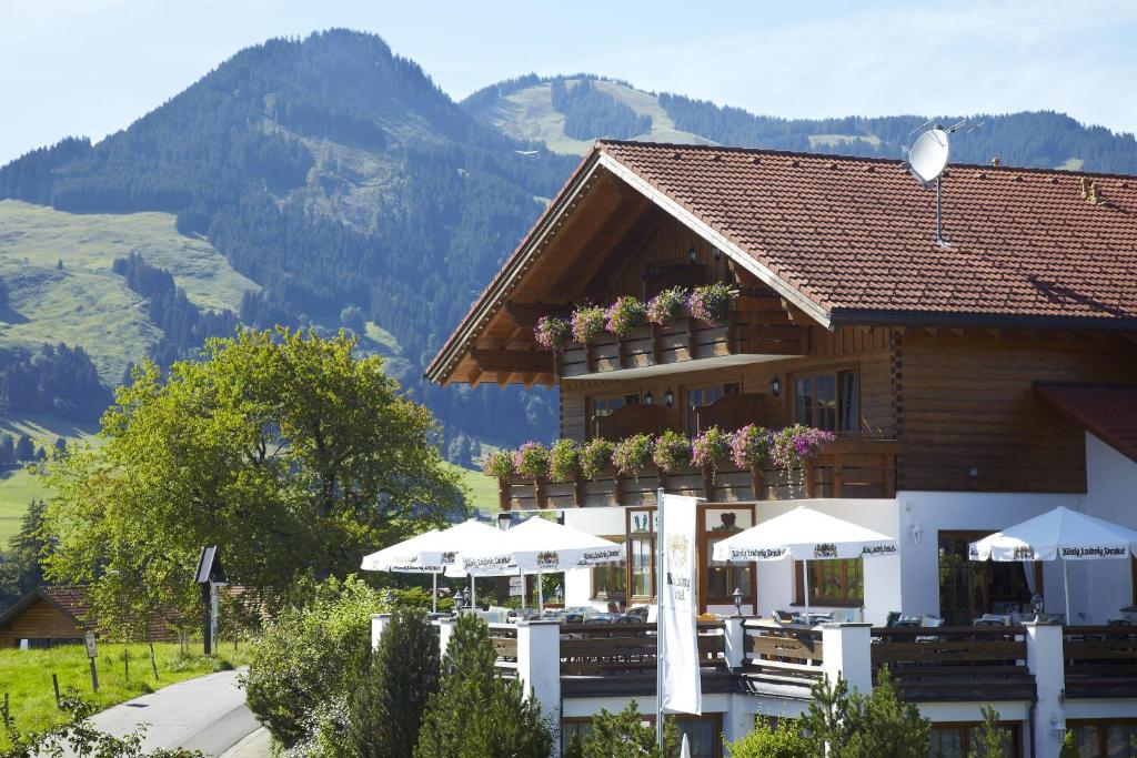 上迈塞尔施泰因Hotel garni Oberdorfer Stuben的一座带桌子和遮阳伞的山地建筑