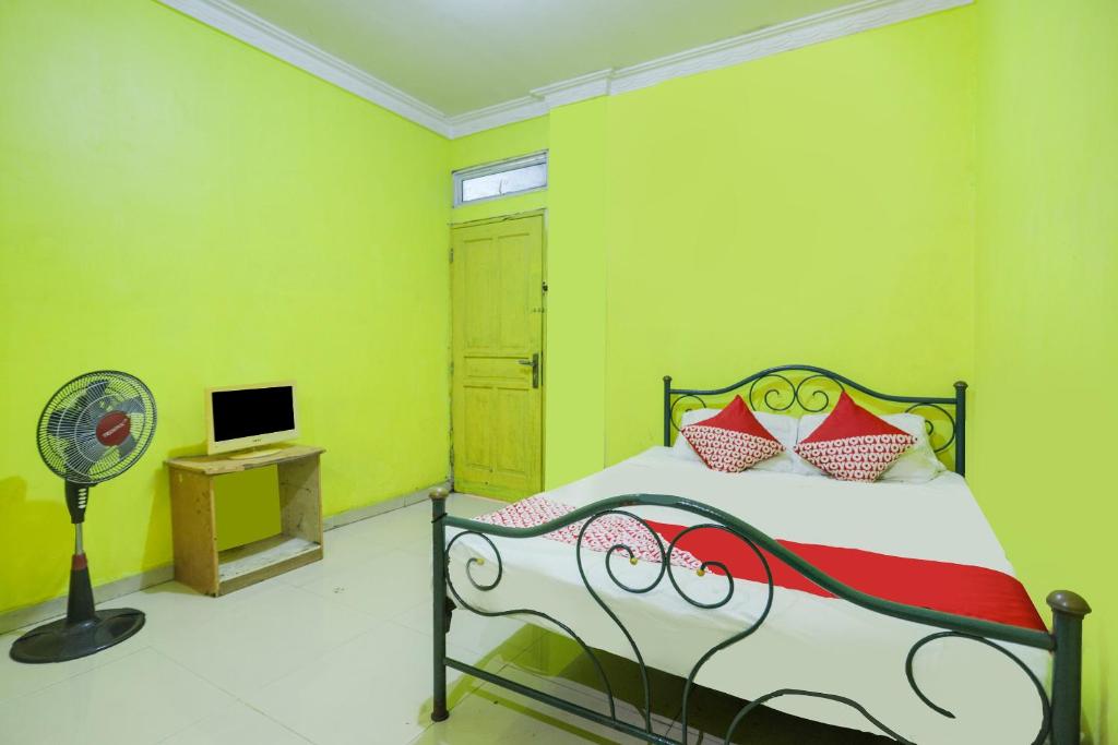 名古屋SPOT ON 91879 Emes Jaya Homestay的一间卧室配有一张带绿色墙壁的床和风扇