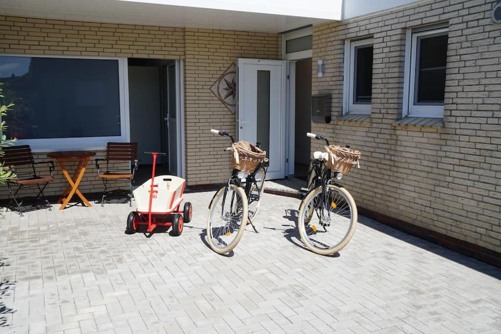 诺登Küsters Ferienhaus Tinchen的两辆自行车停在房子旁边,有一辆婴儿车