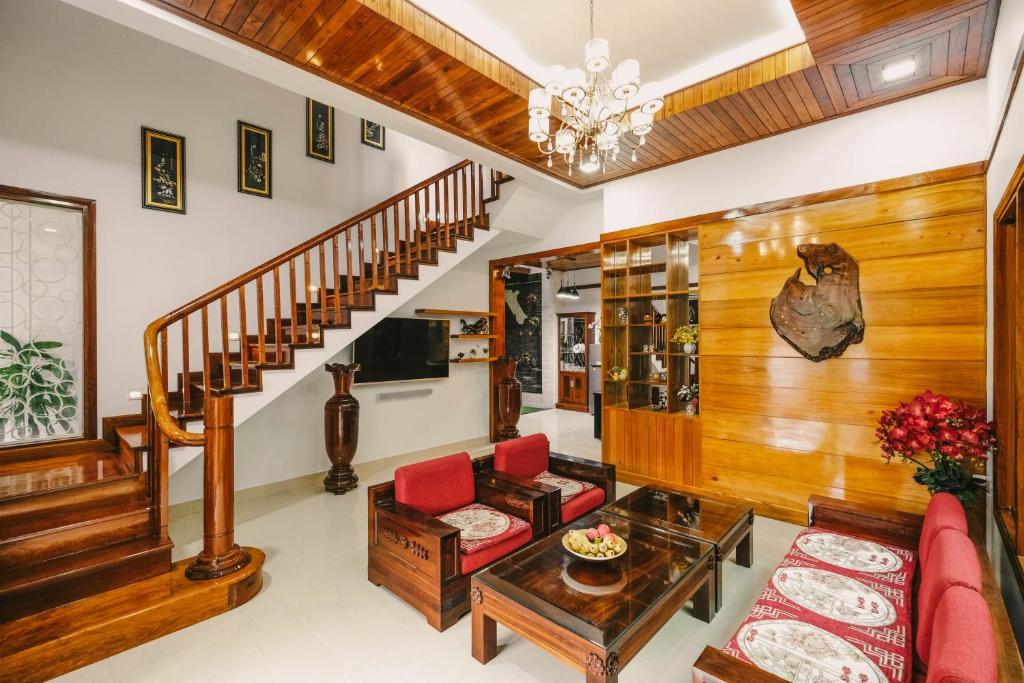 顺化Le Robinet Villa - a journey into Hue citadel soul的一间带楼梯和红色椅子的客厅