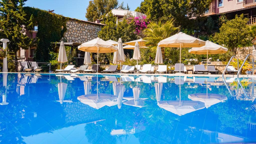 卡尔坎True Blue Boutique Hotel Kalkan的一个带遮阳伞和躺椅的游泳池