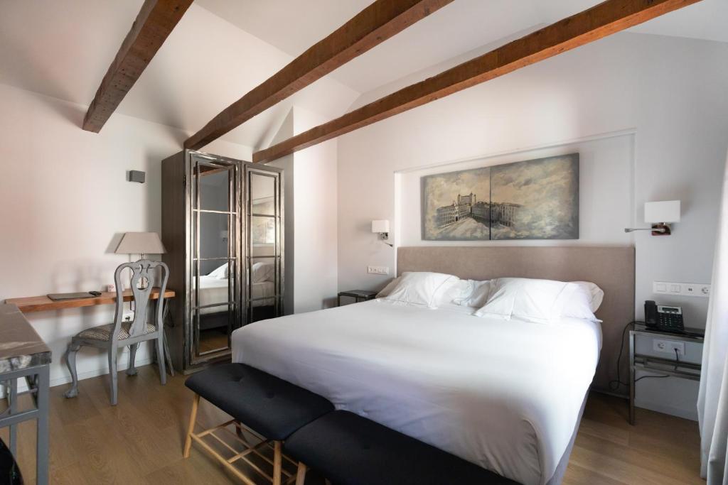托莱多Hospedium Hotel Posada de la Silleria的卧室配有一张白色大床和一张书桌