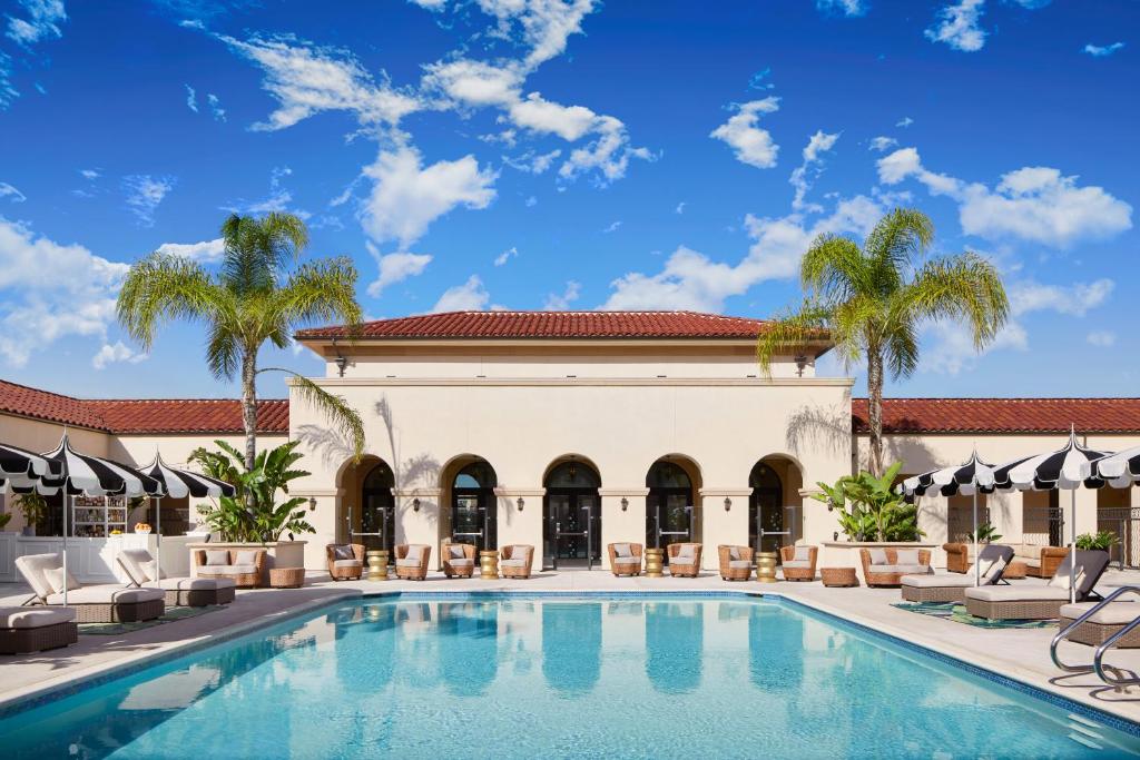 帕萨迪纳Pasadena Hotel & Pool的棕榈树建筑前的游泳池