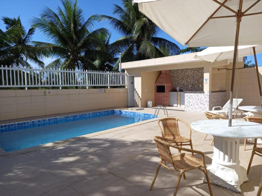 萨尔瓦多Village - Condomínio Mansão da Lagoa的一个带椅子和桌子的游泳池以及一把遮阳伞